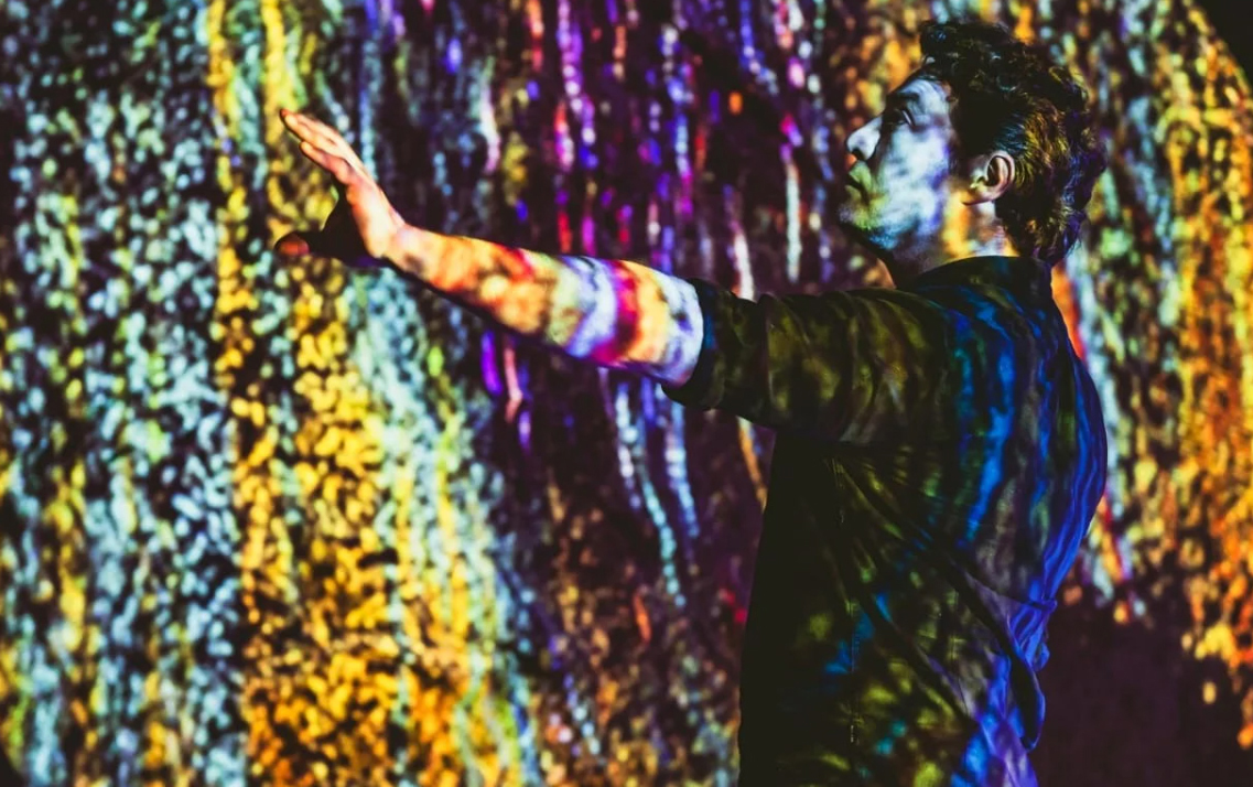 A participant reaches into colourful interactive projections in FLOW.