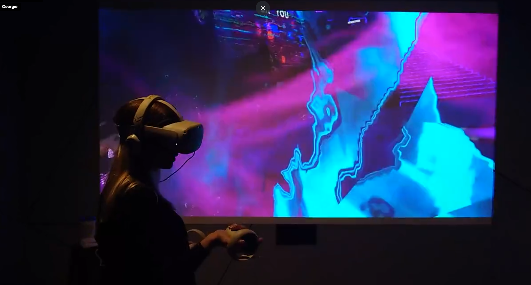 A participant wearing a VR headset in front of vivid digital imagery.