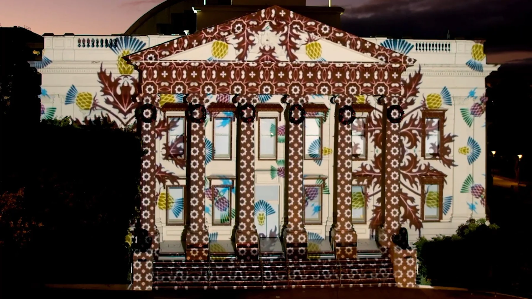 Red, gold and white projection mapping transforms a civic building’s facade.